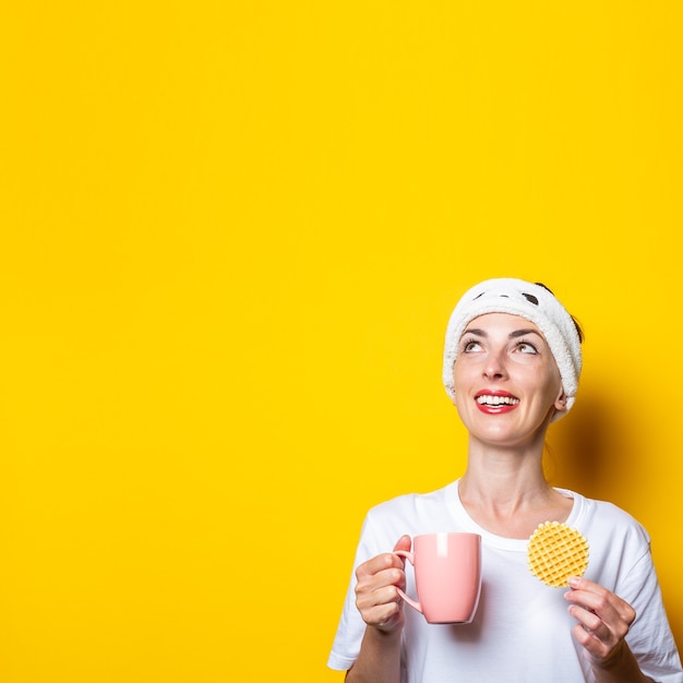 Young girl looking up with a cup of coffee and belgian waffle on a yellow background