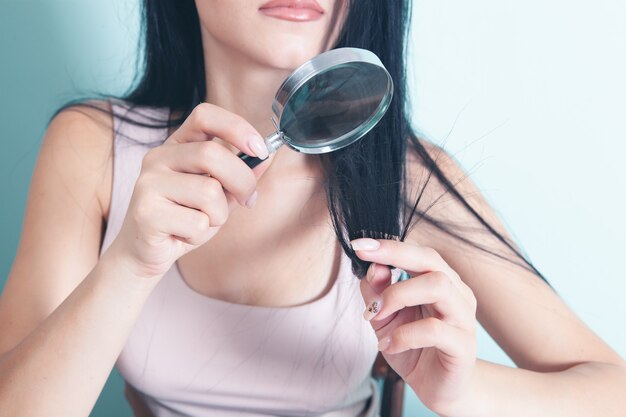 A young girl looks at her hair with a magnifying glass