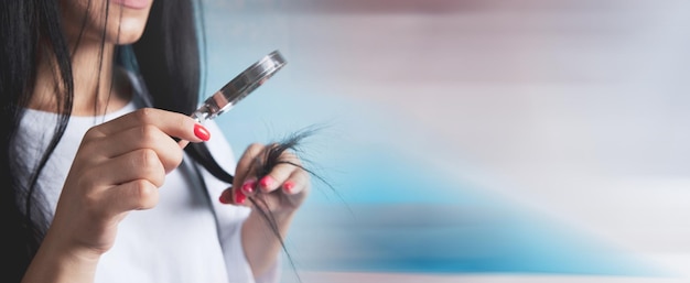 A young girl looks at her hair with a magnifying glass