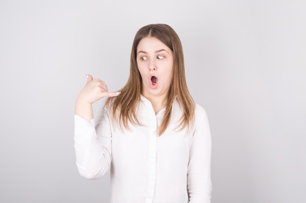 Young girl looks surprised and amazed while watching the phone gesture of her hand. oncept of buying phone and talking.