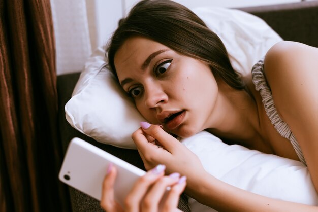 A young girl looks surprised into the phone, overslept