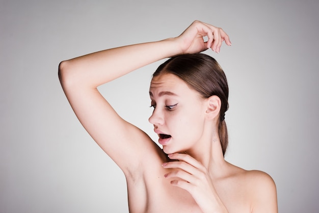 Young girl looks surprised, looks at armpits without hair