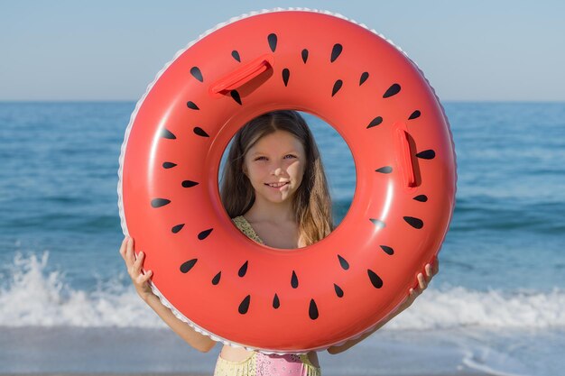 Foto una ragazzina guarda attraverso un anello gonfiabile sulla spiaggia vacanze estive sulla costa del mare