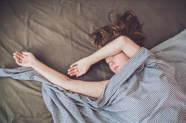 Young girl lying in bed under a blanket