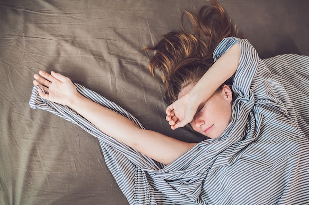 Young girl lying in bed under a blanket