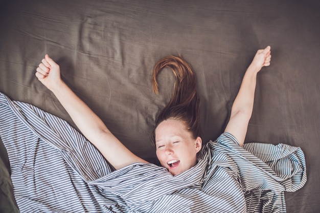 Young girl lying in bed under a blanket