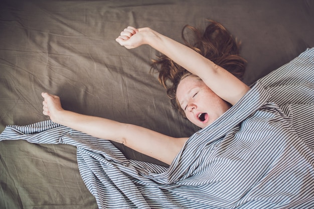 Young girl lying in bed under a blanket