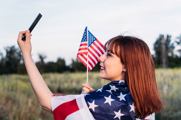 写真 独立記念日を祝い、アメリカの国旗を楽しんでいる自画像を作る少女。 7月4日