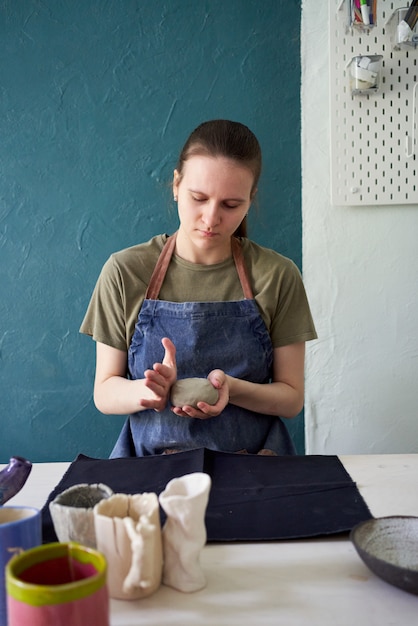 Foto ragazza che fa pentola in ceramica, impastare l'argilla nelle mani. concetto di hobby creativo