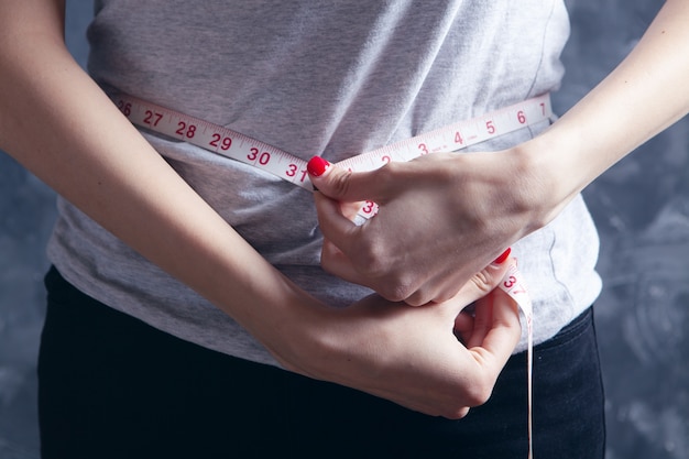 Young girl measures belly with tape