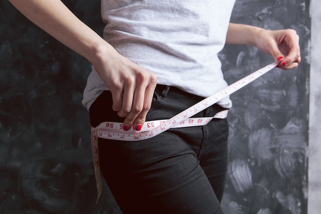 Young girl measuring her waist with a measuring tape