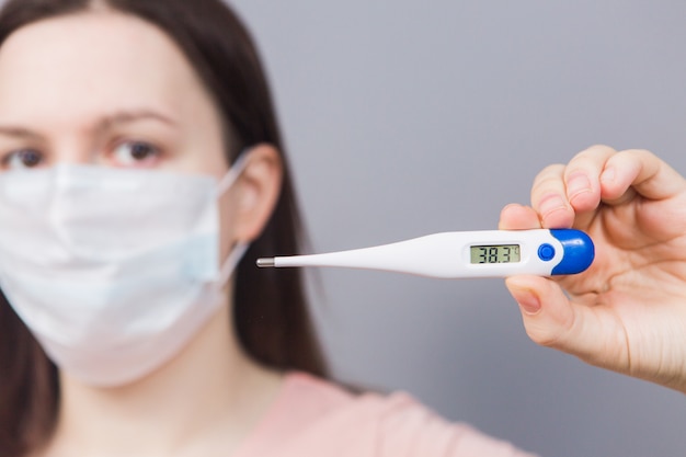 Young girl in medical mask with the text Coronavirus on a gray background. Pandemic, an epidemic in the world. Emotions