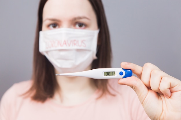 Young girl in medical mask with the text Coronavirus on a gray background. Pandemic, an epidemic in the world. Emotions