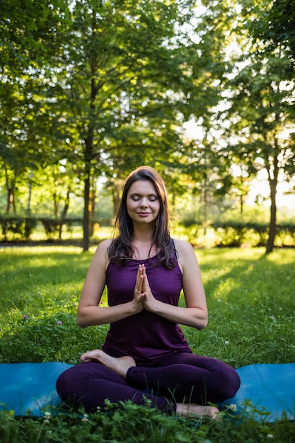 Una ragazza medita su una stuoia di yoga in natura