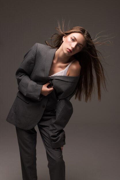 Young girl model in grey man suit standing in studio