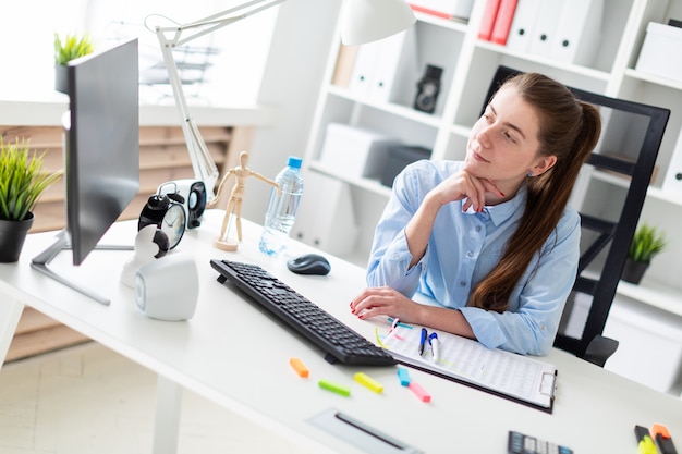 オフィスの若い女の子は、コンピューターの机に座っています。