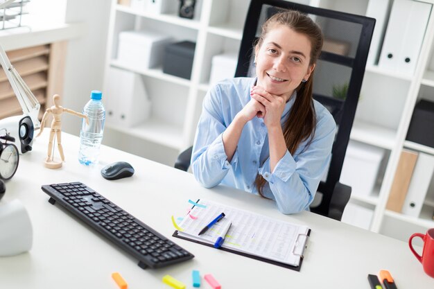 Photo young girl in the office sits at the computer desk.