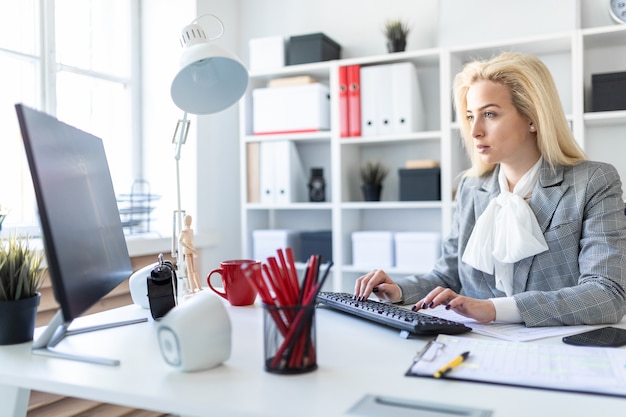 Ragazza in ufficio che lavora con il computer e i documenti.