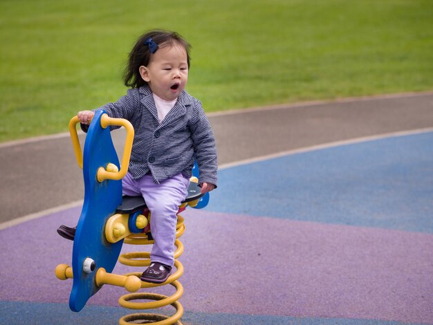 写真 遊び場の機器に乗った少女