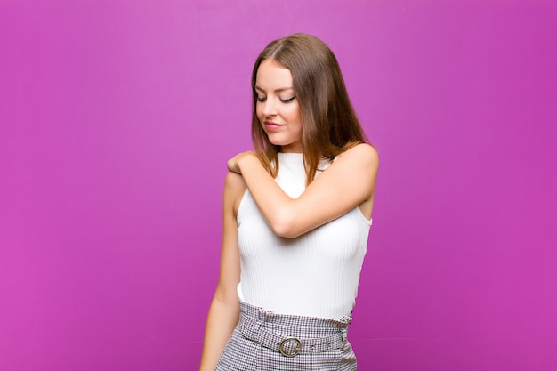 Фото Молодая девушка на фиолетовом фоне чувствует усталость от боли в спине или шее