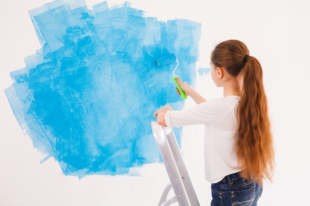 Young girl paints wall