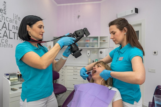 写真 治療プロセスを比較するために歯科で歯の写真を撮る若い女の子の患者