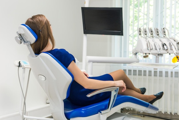 Young girl patient waiting for a doctor in a dental chair at the clinic