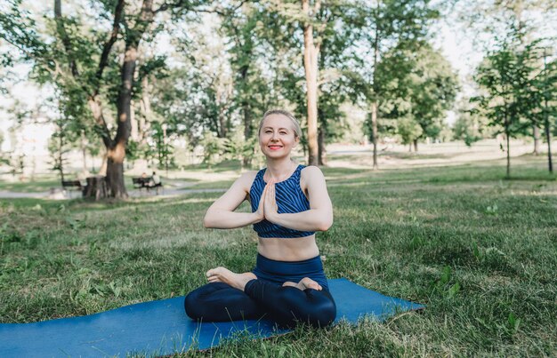 Young girl perform complex yoga exercises in the park outdoors