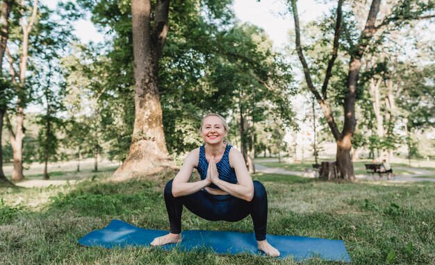 Young girl perform complex yoga exercises in the park outdoors