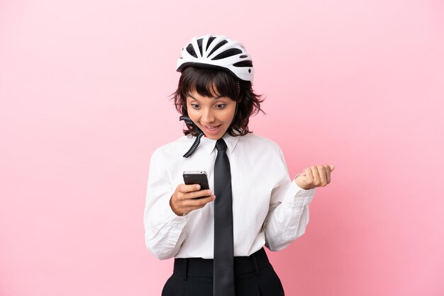 Young girl person with a bike helmet isolated on pink background surprised and sending a message