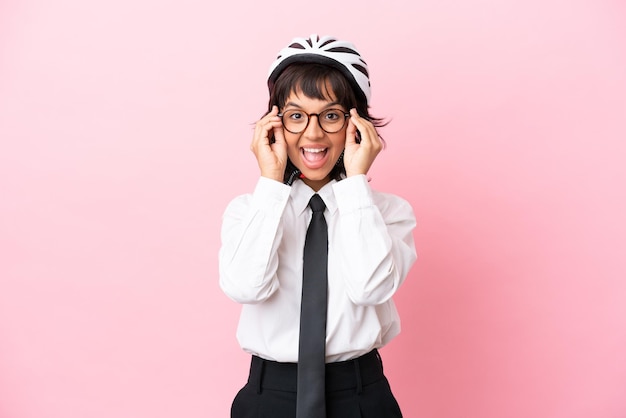 Persona giovane ragazza con un casco da bici isolato su sfondo rosa con occhiali e sorpreso