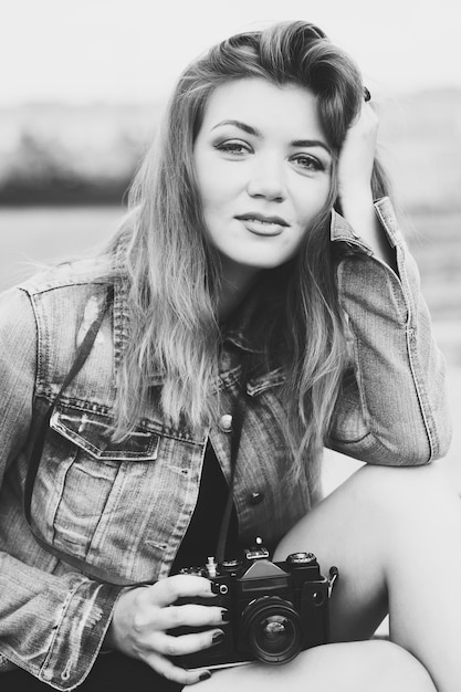 Young girl photographer walking along the street in a jeans jacket with an old camera