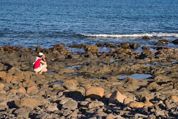사진 냉각 용암에서 화산암으로 형성된 거친 지형 해변을 촬영하는 어린 소녀