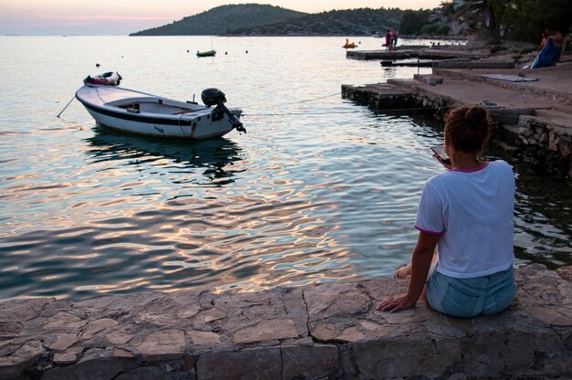 A young girl on the pier at sunset looks at the sea relax