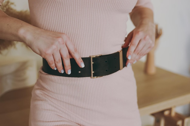 Young girl in a pink dress trying on a leather belt