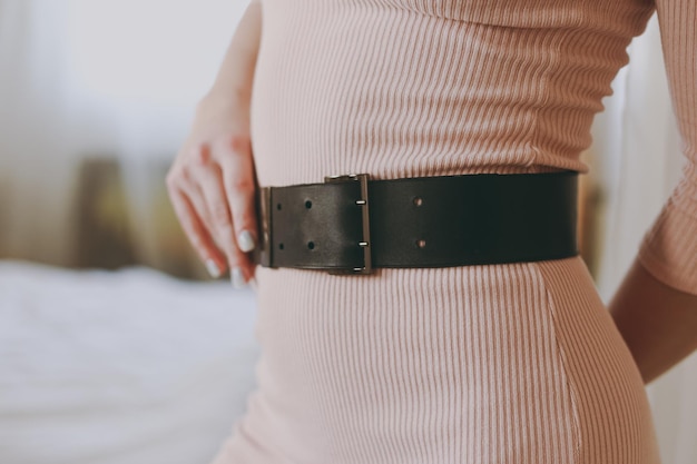 Young girl in a pink dress trying on a leather belt