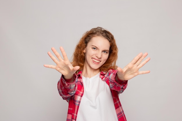 A young girl in a plaid shirt hugs on a light background