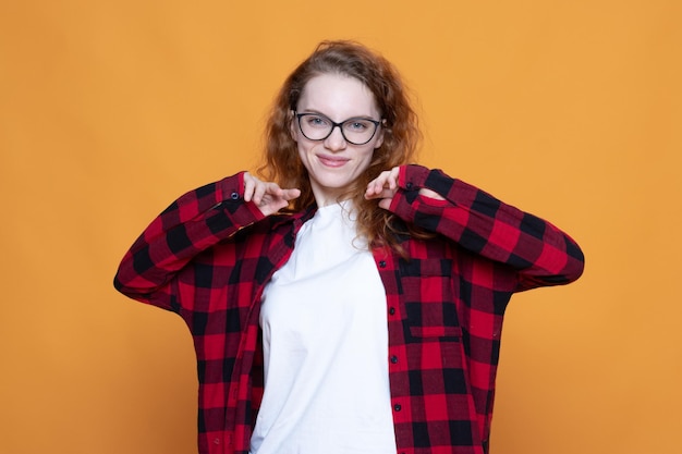 Foto ragazza in camicia a quadri con occhiali su sfondo arancione