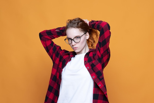 Photo young girl in a plaid shirt with glasses on an orange background