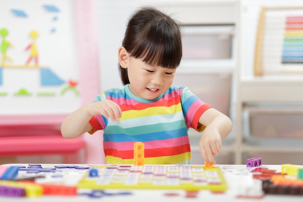 若い女の子が家庭教育のためにナンバーブロックをプレイする