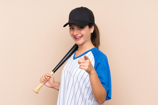 Young girl playing baseball over isolated  surprised and pointing front