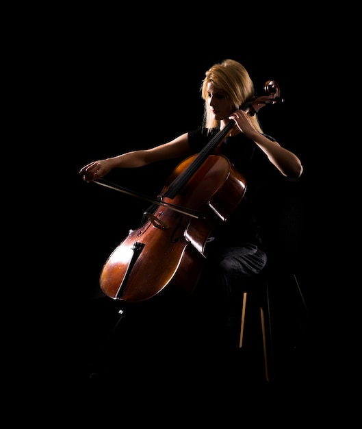 Молодая девушка играет на виолончели на черном фоне
