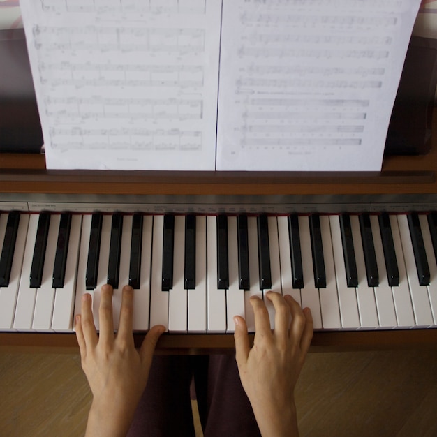 Young girl playing digital piano. Top view