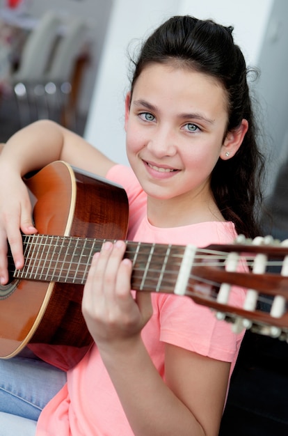 Young girl playing a guitar at home