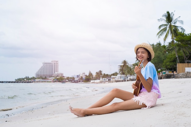 Young girl playing ukulele on the beach