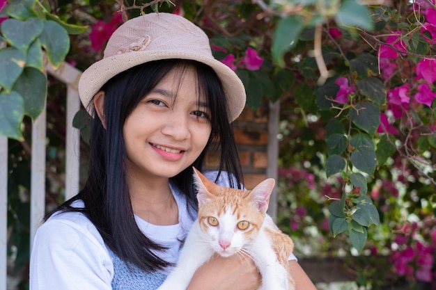 Young girl playing with a cat standing under the flower tree