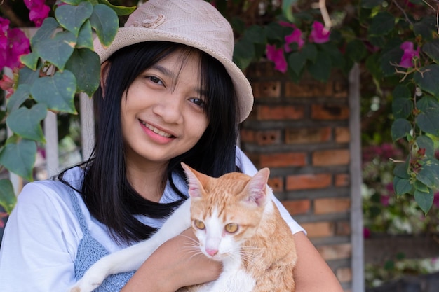 Young girl playing with a cat standing under the flower tree