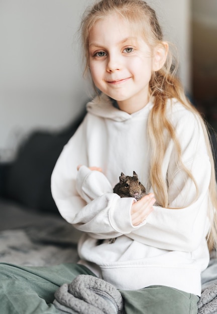 Young girl playing with small animal degu squirrel
