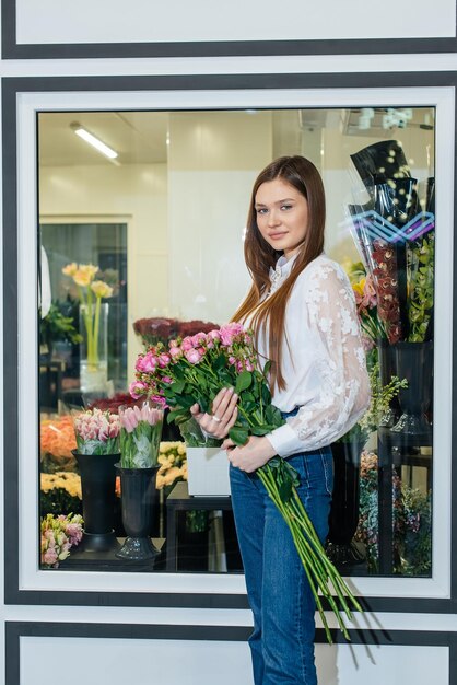 A young girl poses with a beautiful festive bouquet against the background of a cozy flower shop Floristry and bouquet making in a flower shop Small business