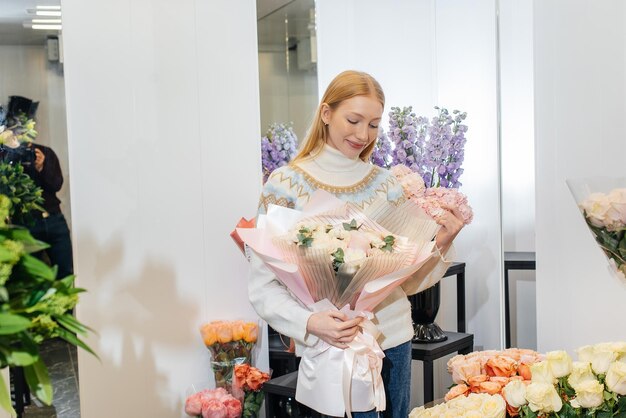 A young girl poses with a beautiful festive bouquet against the background of a cozy flower shop Floristry and bouquet making in a flower shop Small business